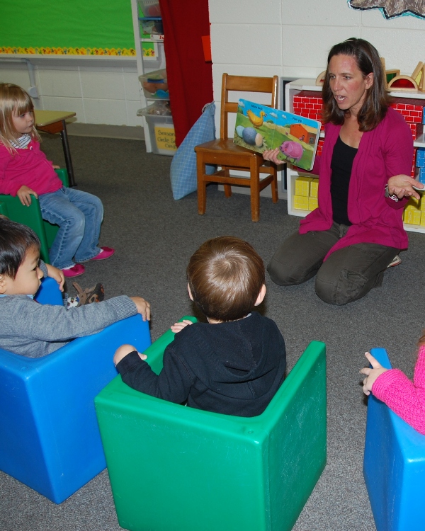 ''Miss Danielle'' reads and discusses a book with fascinated toddlers.